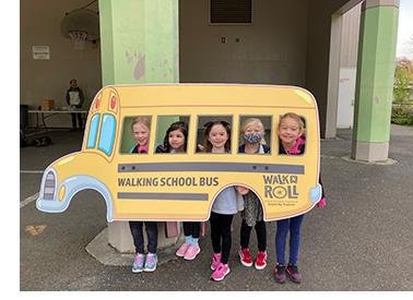 Children holding a cut out of a school bus