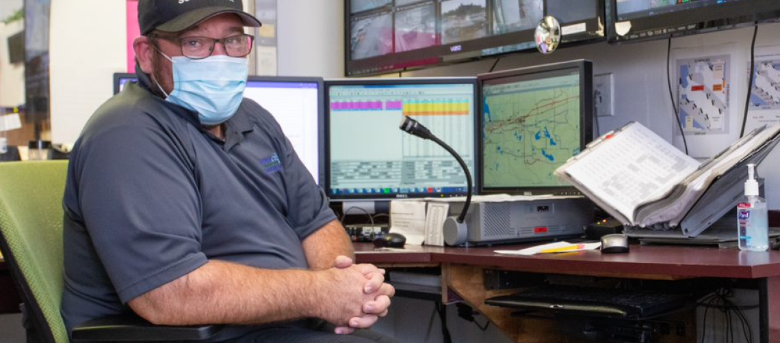 an operations supervisor sitting at the operations dispatch counter, wearing a face mask and ready to dispatch