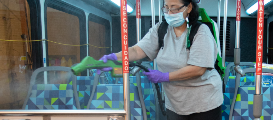 a woman cleans the inside of an Intercity Transit bus while wearing PPE.